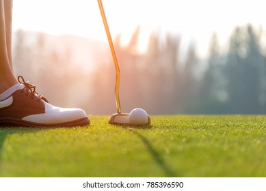 Golfer asian woman putting golf ball on the green golf on sun set evening time.  Healthy and Lifestyle Concept.