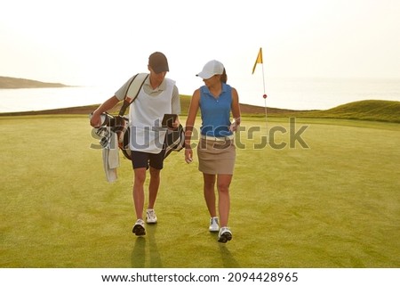 Golfer and caddy walking on golf course