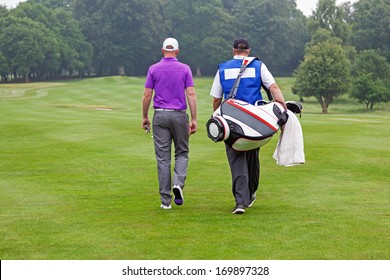 Golfer and caddy walking towards a ball on a par 4 fairway. 