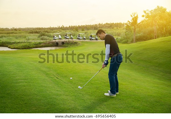 Golfer chip iron short swing\
hit golf ball, sunset golf course scene background with copy\
space.