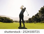 A golfer executes a powerful swing, showcasing follow-through on the fairway under bright sunlight, symbolizing precision and skill.