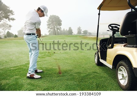 golfer in fairway with cart playing shot towards green