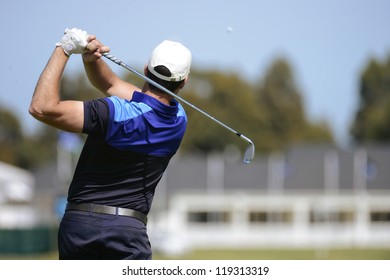 Golfer hits an fairway shot towards the club house