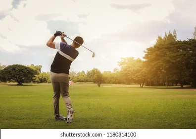 Golfer hitting golf shot with club on course at evening time. - Powered by Shutterstock