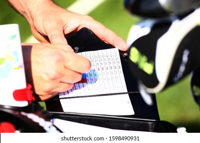 Golfer Keeping Scores In Score Sheet With Hands