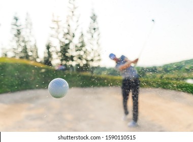 Golfer male shooting amazing shot ball from sand bunker. golfer hitting golf ball with sand blast.blur background, concept strengthens the body , healthy,copy space for put text