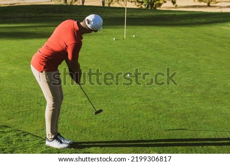 golfer practicing putter technique, alignment, grip and stance on the putting green at the golf driving range. Golf practices. Golf putter stroke to the hole. golfer hitting training putt in the hole