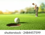 Golfer putting golf ball to the hole on green golf.