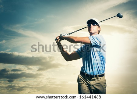 Golfer at sunset, Man swinging golf club with dramatic sunset sky 