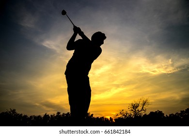 Golfer swing hit golf ball, silhouette sunset scene.