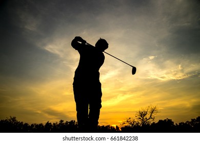 Golfer swing hit golf ball, silhouette sunset scene.