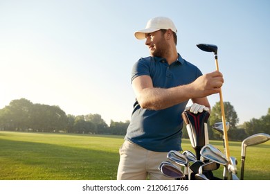 Golfer taking putter before playing golf on green lawn at warm sunny day. Concept of entertainment, recreation, leisure and hobby outdoors. Young caucasian man looking away - Powered by Shutterstock