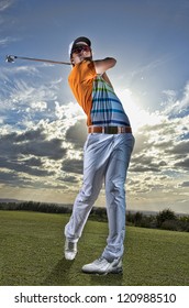 Golfer tees off in late afternoon light