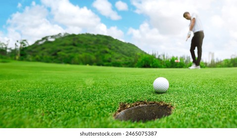 Golfer is using a putter to put a golf ball on the green. sport golf club