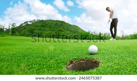 Golfer is using a putter to put a golf ball on the green. sport golf club