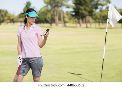 Golfer woman using phone while standing on field - Powered by Shutterstock