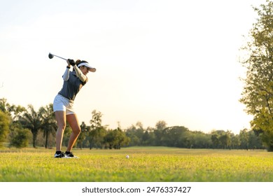 Golfer women sport course golf ball fairway. People lifestyle woman playing game golf swing tee of on the green grass sunset background. Asian female player game shot in summer. copy space for text - Powered by Shutterstock