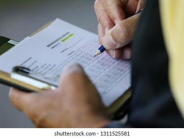 a golfer writes on his scorecard during a golf tournament - Powered by Shutterstock