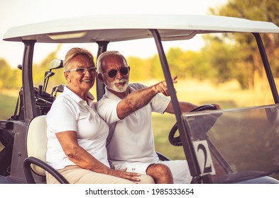  Golferpaar reiten in einem Golfwagen und reden. 