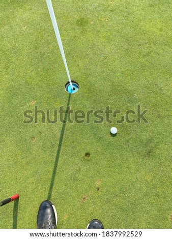 Golfers heartache, close and yet so far away. Golf ball with landing divot and hole with pin and shadow.