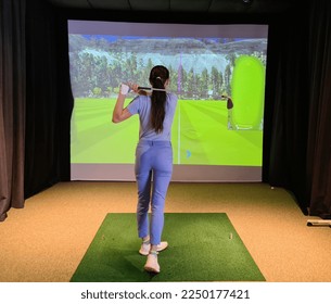 Golfers hitting ball with golf club from indoor court. Playing golf on a golf simulator - Powered by Shutterstock