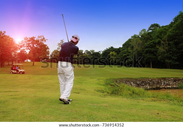 Golfers are playing golf and golf car in the\
evening golf course in\
thailand