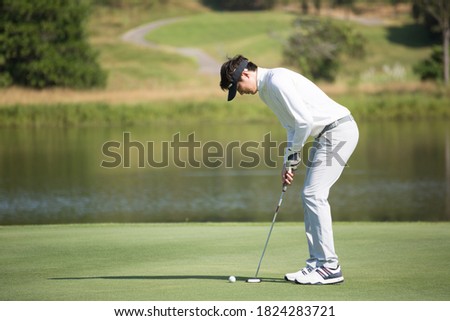 Golfers putting golf balls on the green amid the warm sunshine in the morning. Concept of Outdoor activities and Outdoor sports, Concept of Golfer and Lifestyle.	