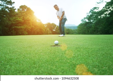 Golfers are putting golf in the evening golf course, on sun set evening time.                               