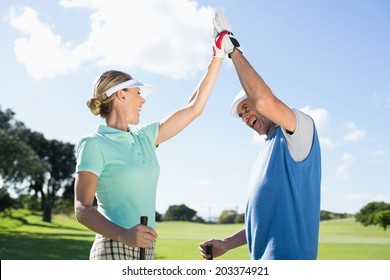 Golfing couple high fiving on the golf course on a sunny day at the golf course - Powered by Shutterstock