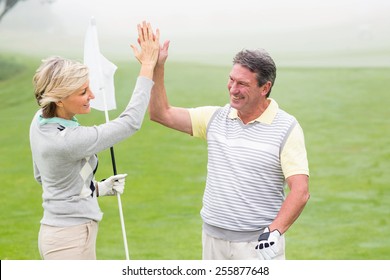 Golfing couple high fiving on a foggy day at the golf course - Powered by Shutterstock