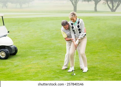 Golfing Couple Putting Ball Together On A Foggy Day At The Golf Course