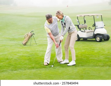 Golfing Couple Putting Ball Together On A Foggy Day At The Golf Course