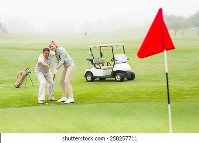 Golfing Couple Putting Ball Together On A Foggy Day At The Golf Course