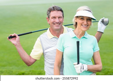 Golfing Couple Smiling At Camera Holding Clubs On A Foggy Day At The Golf Course