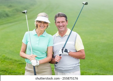 Golfing Couple Smiling At Camera Holding Clubs On A Foggy Day At The Golf Course