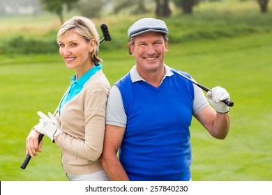 Golfing Couple Smiling At Camera On The Putting Green On A Sunny Day At The Golf Course