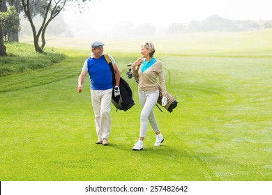 Golfing Couple Walking On The Putting Green On A Foggy Day At The Golf Course