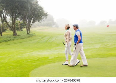 Golfing Couple Walking On The Putting Green On A Foggy Day At The Golf Course