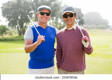 Golfing Friends Smiling At Camera Holding Clubs At The Golf Course