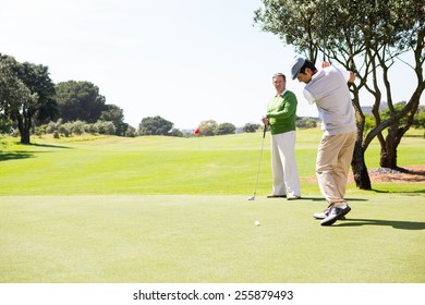 Golfing Friends Teeing Off At The Golf Course