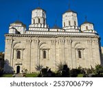 Golia Monastery in Iași, a Romanian Orthodox church with intricate details, featuring multiple domes topped with crosses against a vibrant blue sky