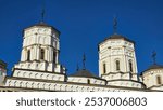 Golia Monastery in Iași, a Romanian Orthodox church with intricate details, featuring multiple domes topped with crosses against a vibrant blue sky