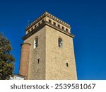 Golia Tower in Iași, Romania, with its unique brickwork and distinctive arched windows, standing tall against a vibrant blue sky.