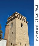 Golia Tower in Iași, Romania, with its unique brickwork and distinctive arched windows, standing tall against a vibrant blue sky.