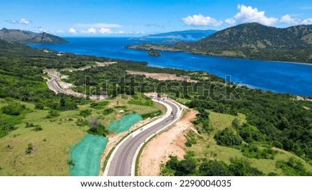 Golo Mori – Labuan Bajo Super Premium Tourism Destination where Asean Summit will implement. Aerial view of a road in green meadows and hills with beach and mountains.