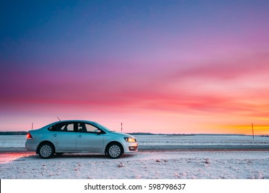 Gomel, Belarus - January 26, 2017: Volkswagen Polo Car Sedan Parking On A Snowy Roadside Of Country Road On A Background Of Dramatic Sunset Sky At Winter Season. There are spots of dirt on a car door