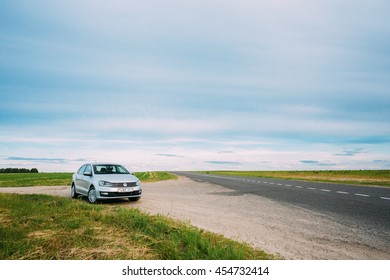 Gomel, Belarus - June 13, 2016: Volkswagen Polo Car Parking On A Roadside Of Country Road On A Background Of Green Spring Fields Or Meadow In Sunny Day With A Beautiful Blue Sky
