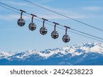 Gondola bubbles against the blue sky and the French Alps in the background. Cable car taking tourists to Fort de La Bastille in Grenoble, France