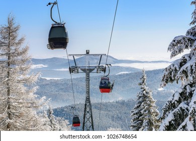 Gondola Cabin Lift In The Ski Resort Over The Forest On The Background Of Snowy Mountains In Sunny Day (high Details)