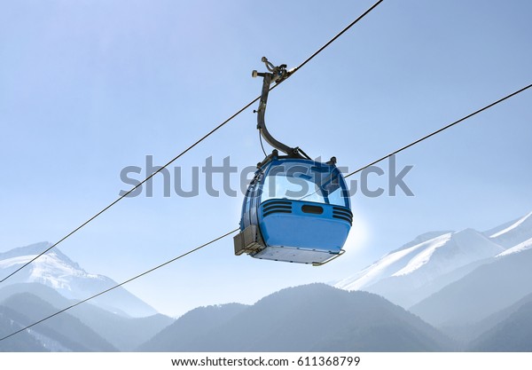 Gondola lift in the ski\
resort in the early morning at dawn with view of mountain ski\
slopes and peaks